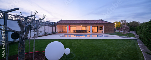 Obraz na plátně Luxurious modern villa at twilight, featuring a serene swimming pool reflecting warm interior lights