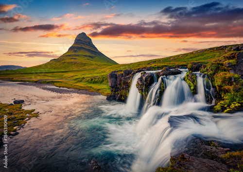 Fantastic summer sunset on Kirkjufellsfoss Waterfall. Stunning evening scene of Kirkjufell peak, Snaefellsnes peninsula location, Iceland, Europe. Beauty of nature concept background.