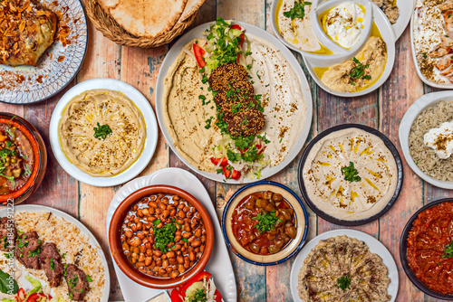 Canvastavla A plate of Lebanese-style baba ghanoush, accompanied by other mezze such as hummus, tabbouleh, and stuffed grape leaves, on a wooden table