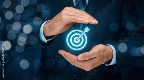 Businessman's hands holding a glowing holographic target with an arrow hitting the bullseye