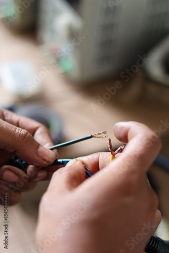 Close-up of hands connecting or stripping insulated electrical wires during wiring installation or repair process.