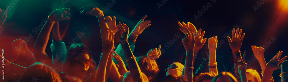 Naklejka premium Dancing crowd silhouettes under dramatic concert lighting. Concept of shared emotions, rhythmic movement, social connection, music immersion and Christmas night celebration atmosphere. Banner