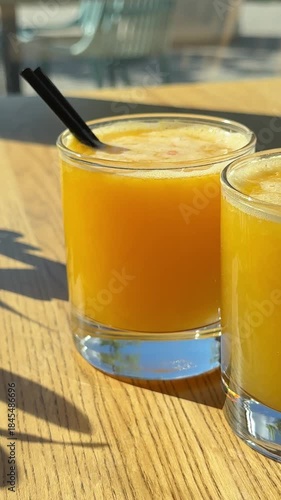 Orange juice in the sun Two glasses. on wooden table by the window an olive branch overlooking the city in a restaurant