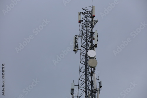 Wireless communication technology uses a steel tower with a cell phone antenna for radio signal transmission to the mobile network in the blue sky