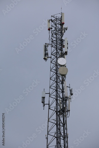 Wireless communication technology uses a steel tower with a cell phone antenna for radio signal transmission to the mobile network in the blue sky
