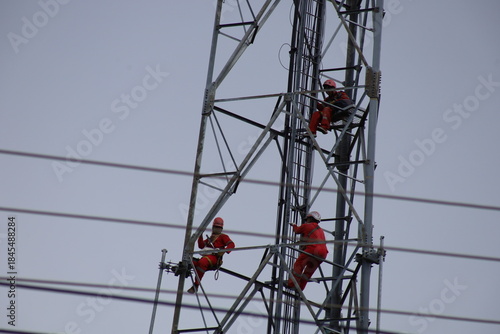 High voltage transmission towers carry electric power cables across the blue sky, supplying energy to industry
