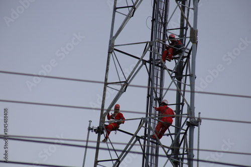 High voltage transmission towers carry electric power cables across the blue sky, supplying energy to industry