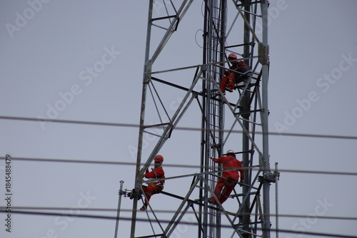 High voltage transmission towers carry electric power cables across the blue sky, supplying energy to industry