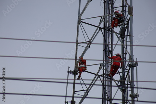 High voltage transmission towers carry electric power cables across the blue sky, supplying energy to industry