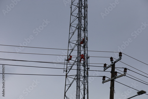 High voltage transmission towers carry electric power cables across the blue sky, supplying energy to industry