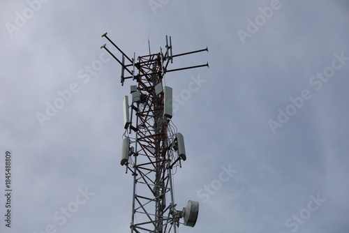 Tower crane and communication antenna on a steel structure construction site against a blue sky, representing wireless telecommunication network technology and the building industry