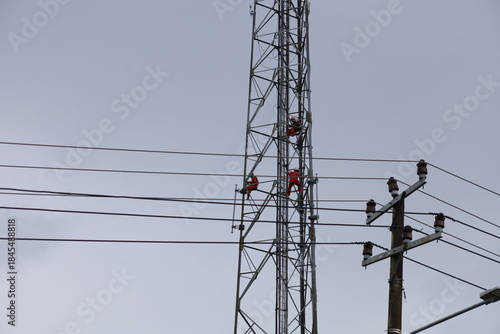 High voltage transmission towers carry electric power cables across the blue sky, supplying energy to industry