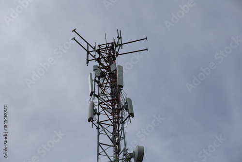 Tower crane and communication antenna on a steel structure construction site against a blue sky, representing wireless telecommunication network technology and the building industry