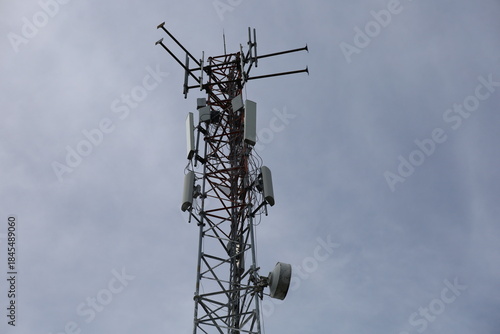 Tower crane and communication antenna on a steel structure construction site against a blue sky, representing wireless telecommunication network technology and the building industry
