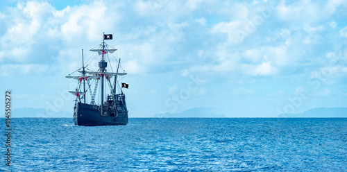 large black pirate ship sailing on ocean, Jolly Roger flag fantasy adventure sea travel, historical galleon vessel, open water horizon, childhood fantasy dream, cultural heritage pioneering spirit
