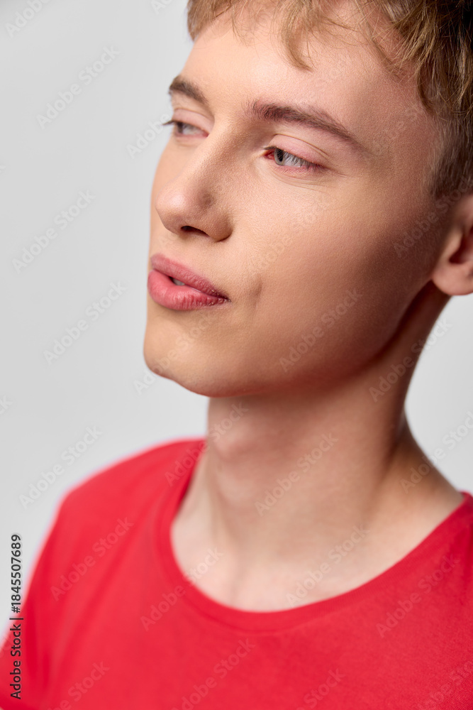 Fototapeta premium Young man, thoughtful profile, closeup of face in a red shirt, calm gaze and soft lighting, minimal background, expressive mood, studio vibe and natural skin tone emphasis