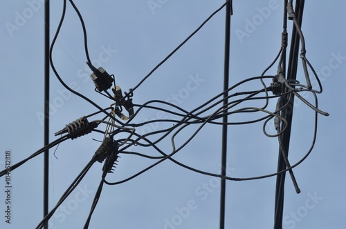 Tangled Overhead Electrical Wires and Cable Connections Against Blue Sky