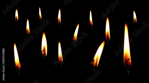 Many burning simple candles in the dark. Many burning candles isolated on a black background. 4K video 60 fps.
