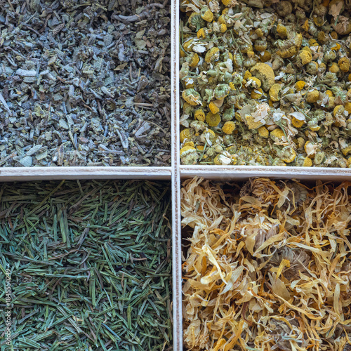 An aesthetic collection of dried herbs, arranged in wooden boxes at the corners, includes lingonberry leaves, chamomile, horsetail, and calendula.