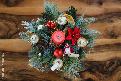 Festive Centerpiece Featuring a Vibrant Arrangement of Holiday Greens, Ornaments, and Candles on a Wooden Table