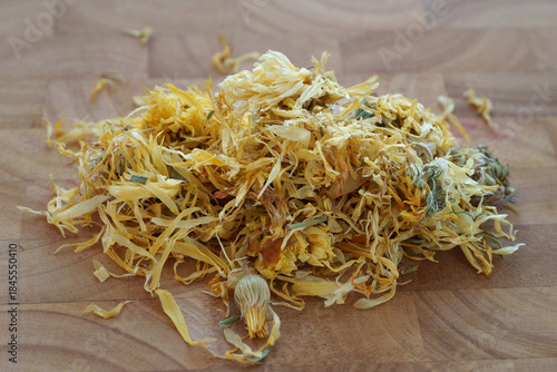 A Closer Look at Dried Calendula Flower Petals Piled on a Wooden Surface for Culinary and Medicinal Uses