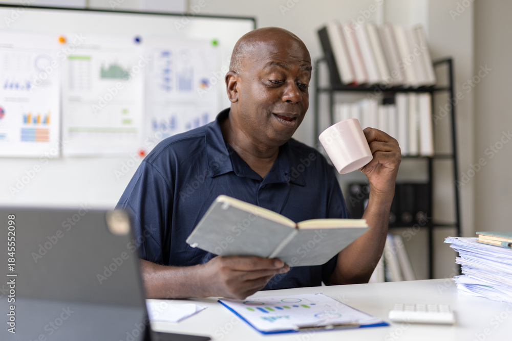 Fototapeta premium Senior businessman drinking coffee and reading notes in office.