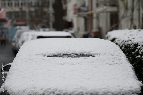 A close-up shot of a car heavily covered in fresh, wet snow on a winter day.