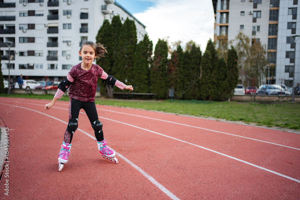 Obraz premium Girl rollerblading on running track wearing protective gear