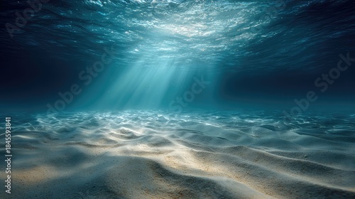 an underwater view of a sunlit ocean floor where the sunlight filters through, creating rays that illuminate the sandy surface
