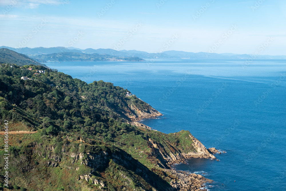 Fototapeta premium Vista panorâmica da costa rochosa de San Sebastián com o mar azul intenso do golfo de Biscaia sob um céu azul em Espanha