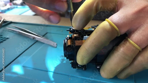 technician is disassembling a DSLR lens at his workshop desk. Close up
