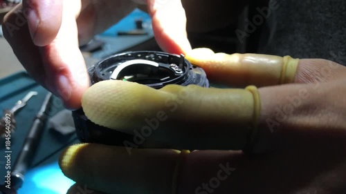technician is assembling a DSLR lens at his workshop desk. Close up