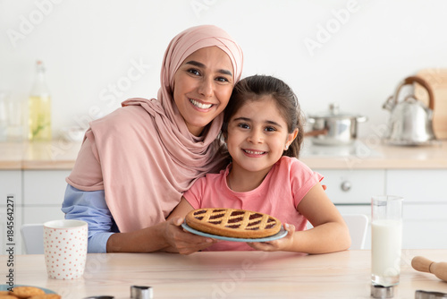 Fotografia A woman and young girl proudly display a freshly baked pie in the kitchen