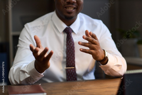 Wallpaper Mural Middle aged Black man gesturing with hands while sitting at desk, wearing formal attire, appearing to explain or discuss topic in professional school principal setting Torontodigital.ca