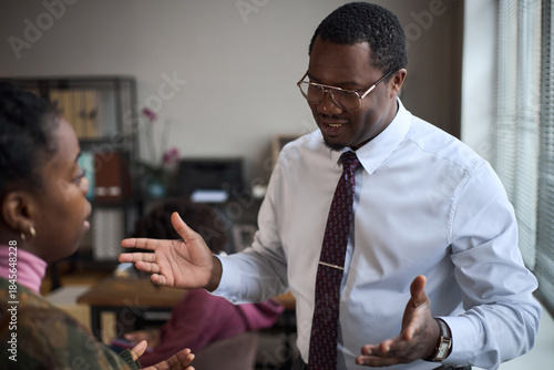 Fényképezés Middle aged Black man gesturing while speaking to young Black woman in office se