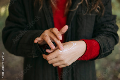 Person applying nourishing hand cream to protect skin from dryness.