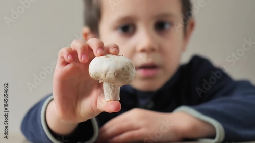 Young Child Holding and Examining a Raw White Button Mushroom