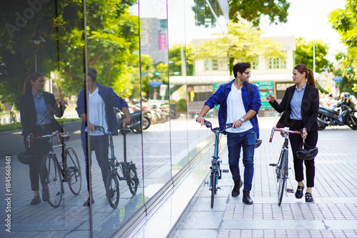 Urban professionals walking with bicycles in modern city environment.