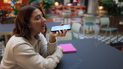 Artificial intelligence receives playful gratitude as woman smiles and flirts with voice assistant appreciating helpful answers and friendly support in everyday digital communication