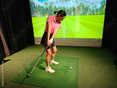 Konstfotografi Golf player swings club in indoor golf simulator at local sports facility during