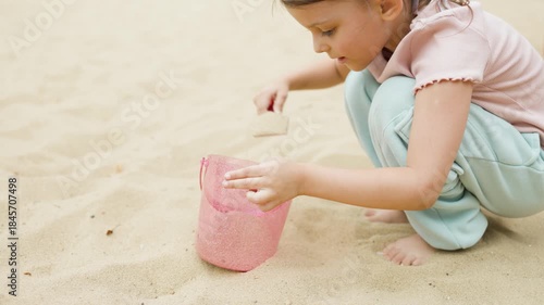 A girl plays in a sandbox on a playground in a park