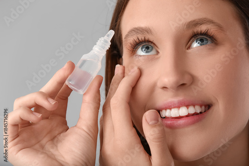 Young woman using eye drops...