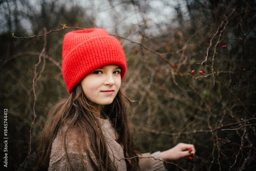 Naklejka premium Preteen girl on walk nature wearing red hat.