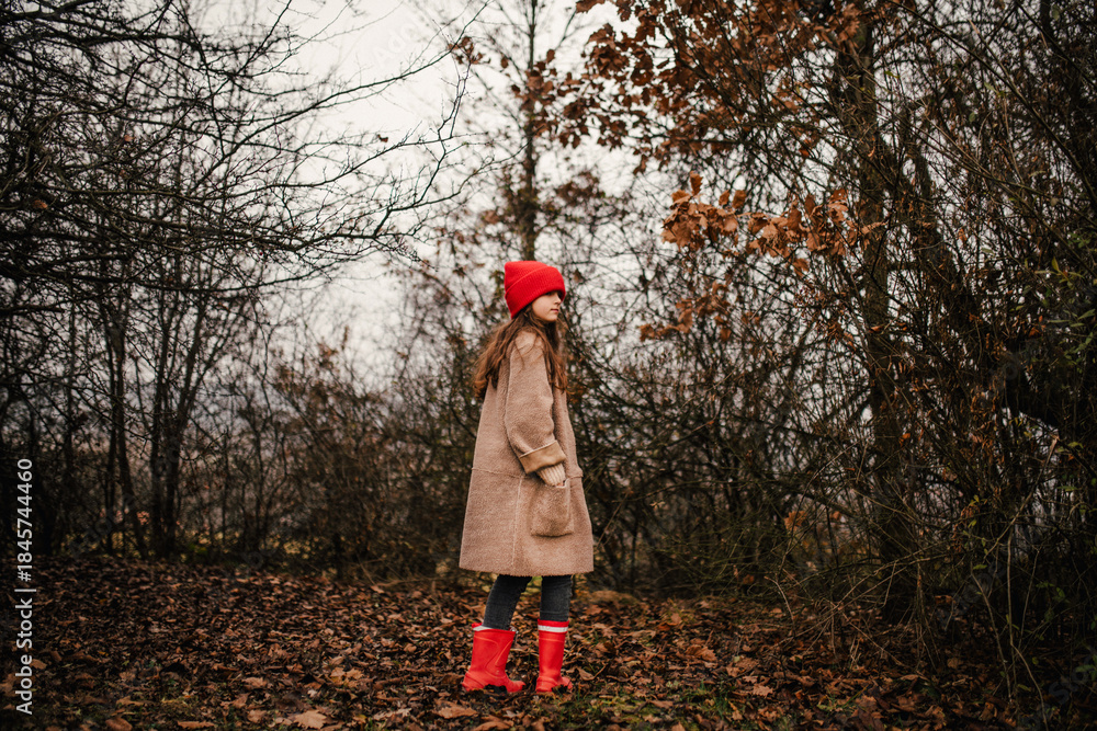 Naklejka premium Young girl standing in nature wearing red hat.