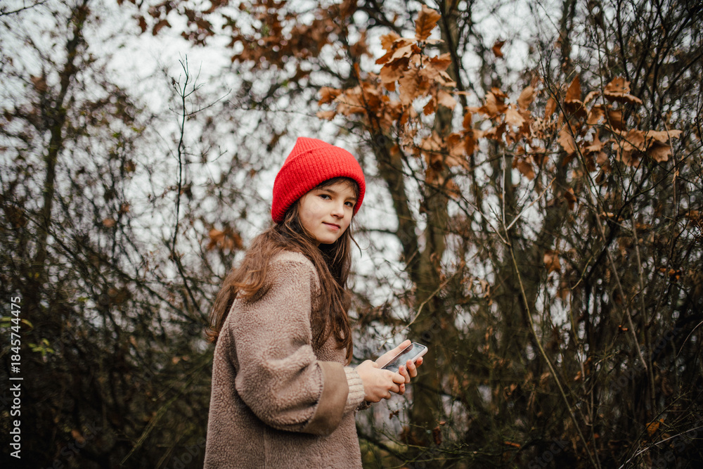 Naklejka premium Young girl standing in nature wearing red hat.