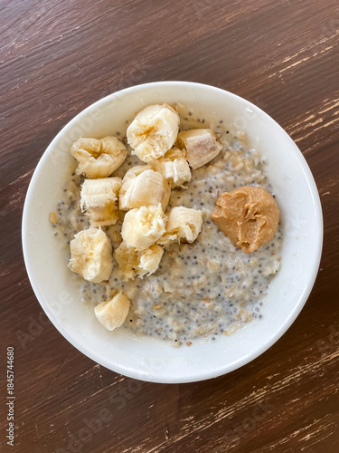Oatmeal with chia seeds, whey protein, banana slices and peanut paste prepared as real everyday breakfast. Simple nutritious meal focused on balance