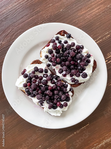 Black rye bread topped with soft cottage cheese and sprinkled with frozen blueberries. Simple real food breakfast or snack with dairy grain and berries