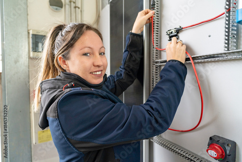 Woman electrician installing wires in electrical panel