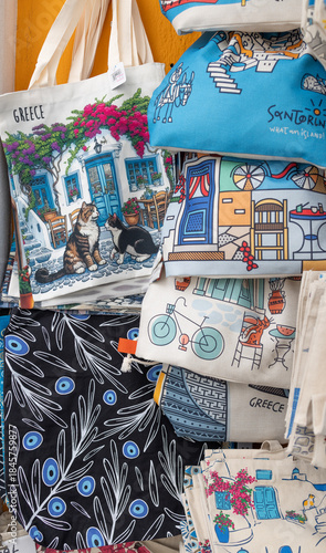 Fototapeta Naklejka Na Ścianę i Meble -  Stack of Greece and Santorini souvenir tote bags and pouches for sale at street vendor, Greece, 4 October 2025