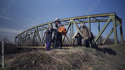 An immigrant family travels by walking on alternative paths through the rural area on a cold sunny day in the winter season